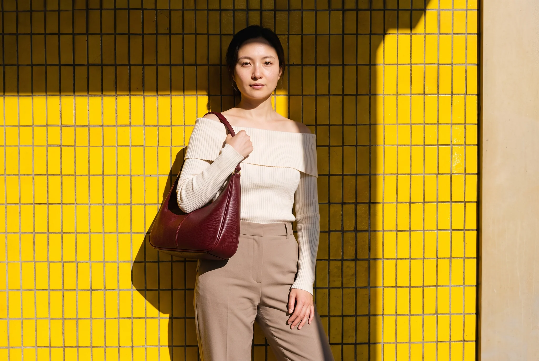 Burgundy hobo bag worn against yellow tiles