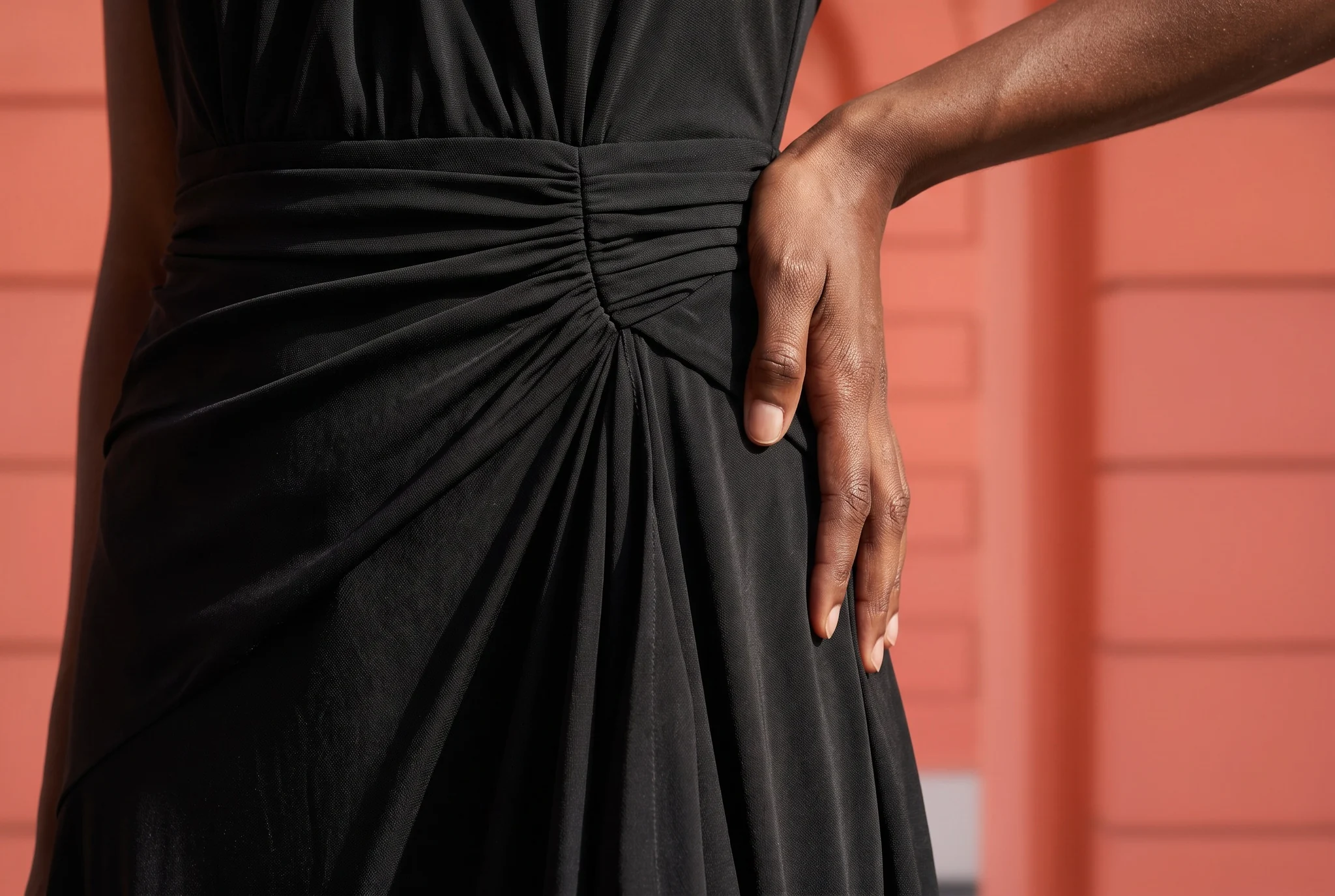 Close-up of the ruched waist and draped skirt of the black halter maxi
